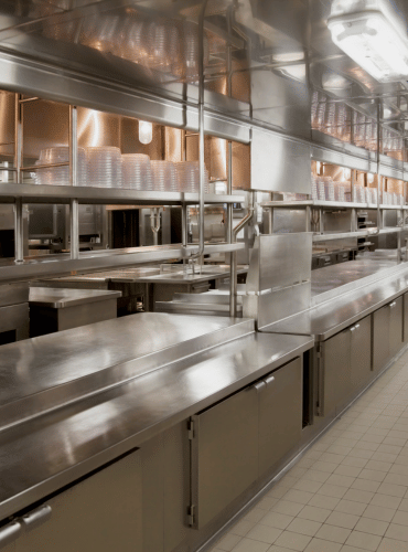 large commercial kitchen with stainless steel shelves and production table