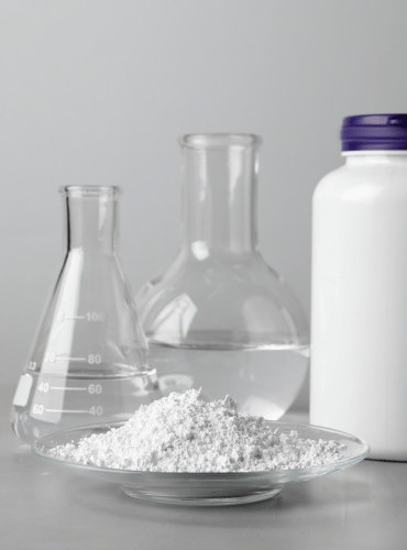 plate with calcium carbonate powder beside a jar and laboratory glassware