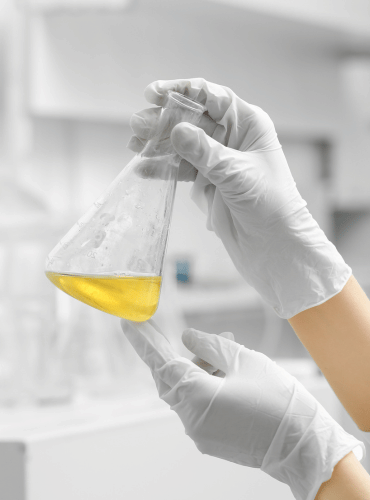 technician holding a flask of oleo chemicals in a laboratory